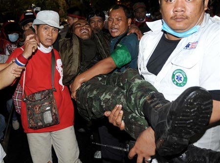 Người biểu tình khiêng một binh sĩ bị thương ra khỏi đám đông trong cuộc đụng độ tối 10/4. Ảnh: AFP.