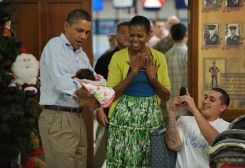 US President Barack Obama and First Lady Michelle Obama hold one-month-old Adeline Valentina Hernandez Whitney as father William Whitney (R) takes a photo while greeting military personnel and their families at Marine Base Hawaii at Kaneohe Bay on Christmas Day, December 25, 2011. Obama greeted base personnel while vacationing at a rental home nearby. US President Barack Obama and First Lady Michelle Obama hold one-month-old Adeline Valentina Hernandez Whitney as father William Whitney (R) takes a photo while greeting military personnel and their families at Marine Base Hawaii at Kaneohe Bay on Christmas Day, December 25, 2011. Obama greeted base personnel while vacationing at a rental home nearby.