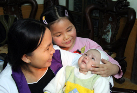 Chị Thơm cùng cô con gái hạnh phúc bên bé trai từng bị bắt cóc. Ảnh: Thái Thịnh.