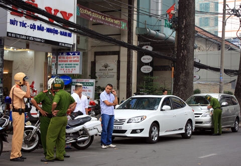 Lực lượng thanh tra giao thông xử phạt xe ôtô cá nhân đậu dưới lòng đường nơi trước đó là bãi giữ xe có thu phí sáng 17/2. Ảnh: Tá Lâm.
