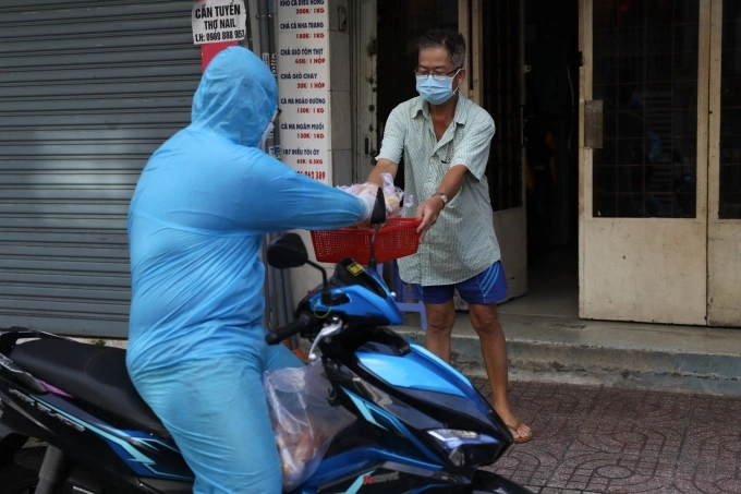 Tình nguyện viên tiếp tế nhu yếu phẩm cho từng nhà trong khu phong tỏa trên đường Vườn Chuối, quận 3, TP HCM, ngày 30/7. Ảnh: Quỳnh Trần