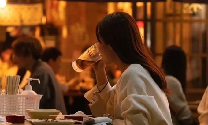 Một cô gái uống bia trong quán ăn ở Nhật Bản. Ảnh: Stanislav Kogiku