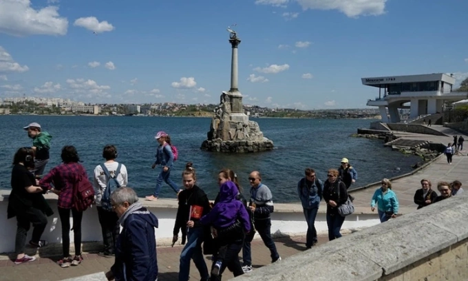 Khách du lịch đi dọc bờ kè của Vịnh Sevastopol gần Đài tưởng niệm Tàu đắm ở Crimea hồi tháng 5. Ảnh: AP.