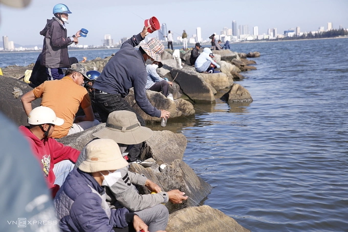Các câu thủ đứng trên cầu Phú Lộc và bờ kè đá thả chai nhựa để bắt cá đối. Ảnh: Ngọc Trường