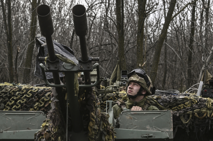 A Ukrainian serviceman looks on as he sits on an anti-air gun near Bakhmut, on March 24, 2023. (Photo by Aris Messinis / AFP)