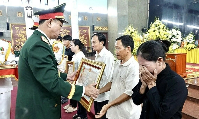 Trung tướng Nguyễn Trường Thắng, Tư lệnh Quân khu 7 trao Huân chương Bảo vệ Tổ quốc hạng Ba cho thân nhân 12 liệt sĩ, sáng 8/12. Ảnh: An Phương