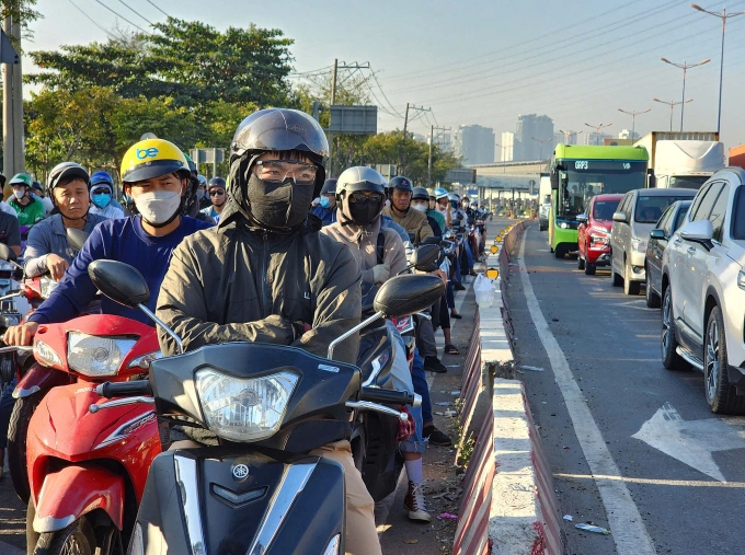 Người dân mặc áo ấm, khoanh tay giữ ấm khi dừng xe máy ở ngã tư Võ Nguyễn Giáp - Tây Hoà, TP Thủ Đức. Ảnh: Đình Văn