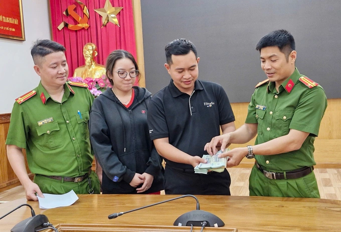 Cảnh sát trao trả lại toàn bộ số tiền bị cướp cho đại diện cửa hàng điện thoại. Ảnh: Công an cung cấp