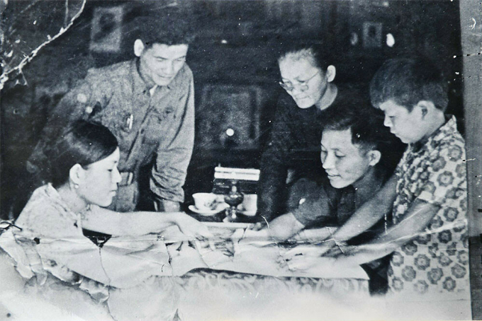 Bên tấm bản đồ ngày 29/4/1975, tại nhà má Sáu, từ trái qua, Phước, Chính ủy Trịnh Văn Thư, má Sáu Ngẫu, Trung đoàn trưởng Nguyễn Huy Hiệu, Đức. Ảnh: Tư liệu báo Quân đội nhân dân