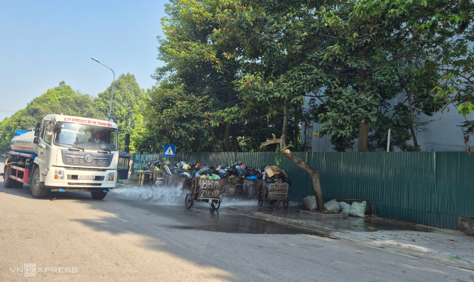 Để giảm mùi hôi thối tại các bãi tập kết rác tạm, công ty môi trường đang cho xe phun nước rửa nền đường. Ảnh: Lê Hoàng