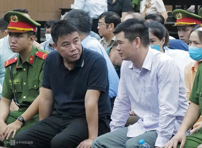 Nguyễn Văn Hậu (áo đen) trò chuyện cùng bạn, giám đốc Trần Hữu Định trước khi tòa làm việc, ngày 25/6. Ảnh: Ngọc Thành