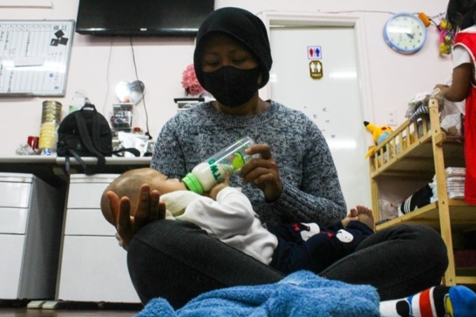 Bảo mẫu cho em bé bú bình trong cơ sở của Harmony Home ở Đài Bắc ngày 27/4. Ảnh: Aljazeera