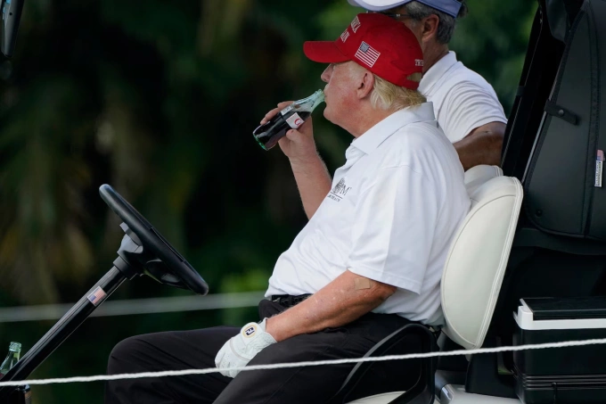 Ông Trump uống Coca tại sân golf ở Florida năm 2022. Ảnh: AP