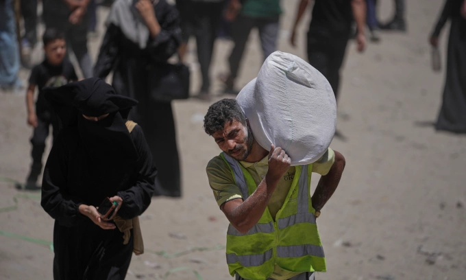 Người dân Palestine vác túi bột mì được viện trợ tại Gaza City hôm 12/7. Ảnh: AP