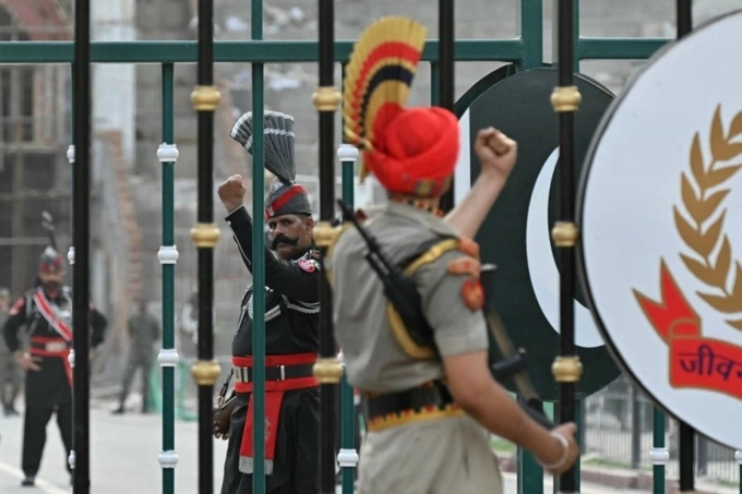 Binh sĩ Ấn Độ và Pakistan giơ nắm đấm về phía nhau trong nghi lễ hạ cờ. Ảnh: AFP