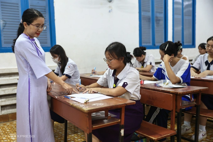 Giám thị hướng dẫn thí sinh điền thông tin tại kỳ thi tốt nghiệp THPT 2025 ở TP HCM. Ảnh: Quỳnh Trần