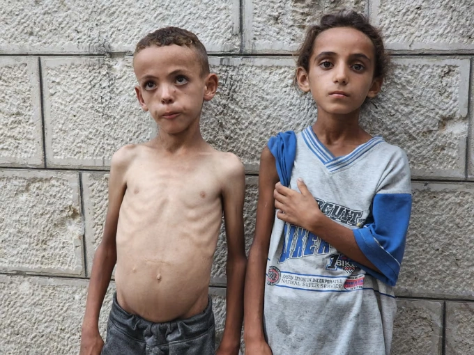 Hai trẻ em Gaza bán vòng tay, xin ăn gần một nhà thờ đổ nát trong thành phố. Ảnh: Guardian