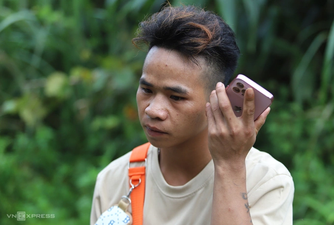 Ngồi nghỉ giữa đường đoạn qua xã Tri Lễ, huyện Quế Phong cũ, anh Nghệ liên tục mở máy điện thoại gọi về cho người thân nhưng không được. Ảnh: Đức Hùng