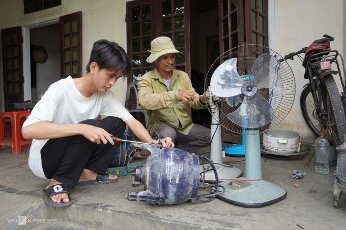Gia Huân sửa đồ điện cùng cha. Ảnh: Phạm Linh