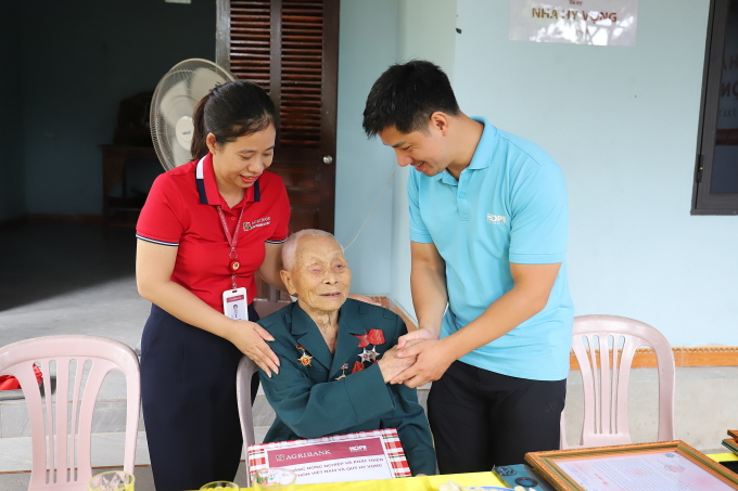 Bà Nguyễn Thị Hạnh (áo đỏ) - Phó giám đốc chi nhánh Hương Khê - Hà Tĩnh - Ngân hàng Agribank trao quà cho cụ Vấn, ngày 25/7/2025.Ảnh: Nga Thanh