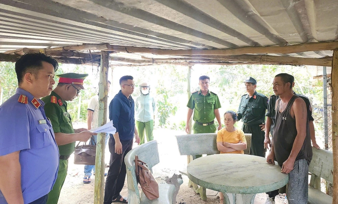 Cơ quan điều tra đọc lệnh bắt Nguyễn Quốc Sơn (áo đen) và vợ Nguyễn Thị Chăng (áo vàng). Ảnh: Dương Đông