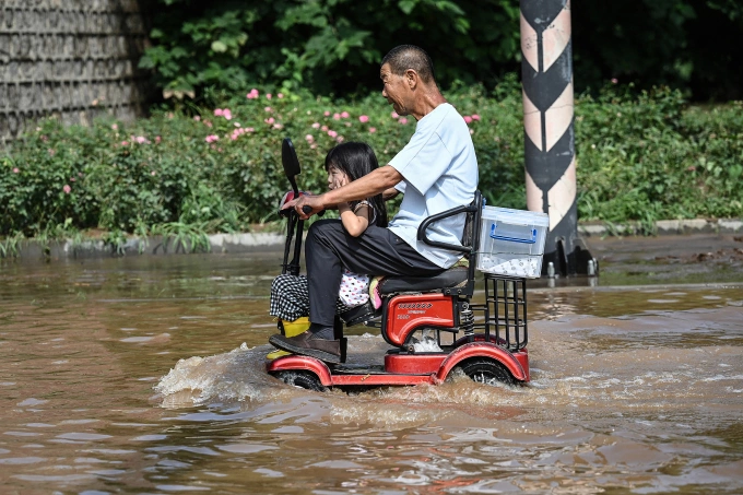 Người dân Mật Vân, Bắc Kinh lái xe qua con phố ngập nước, ngày 28/7. Ảnh: AFP