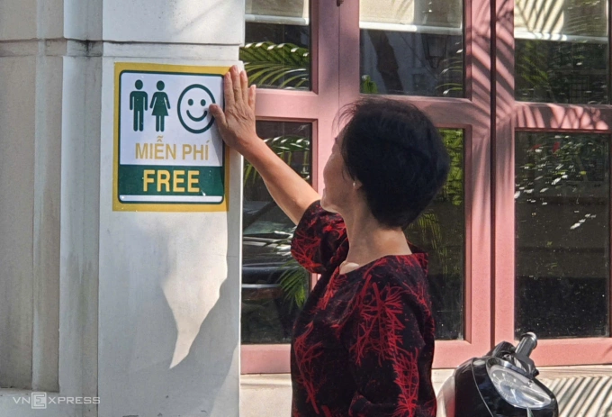 Đại diện tổ dân phố đi vận động, dán logo vệ sinh miễn phí tại một cửa hàng trên phố Phan Chu Trinh, phường Cửa Nam, sáng 2/8. Ảnh: Võ Hải