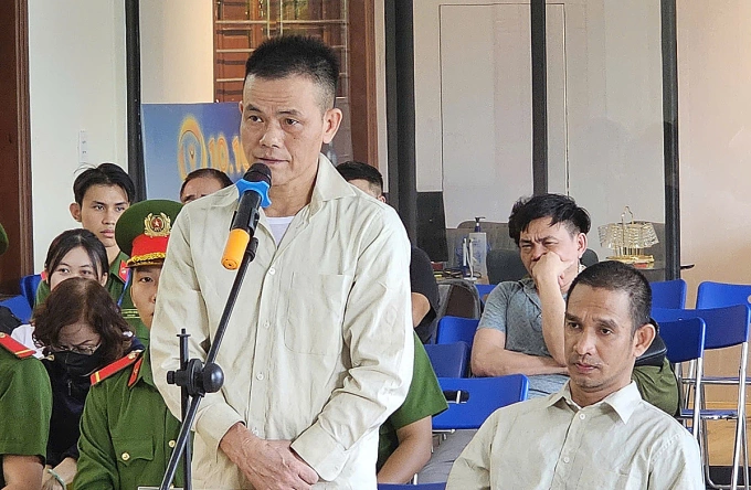 Trần Kim Hoàn (đứng) và Trần Bảo Quốc (ngồi) tại tòa. Ảnh: Ngọc Hoa