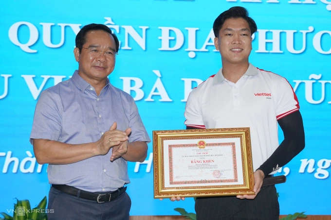 Ông Nguyễn Văn Được trao bằng khen cho Cao Thành Đạt, người cứu bé gái. Ảnh: Trường Hà