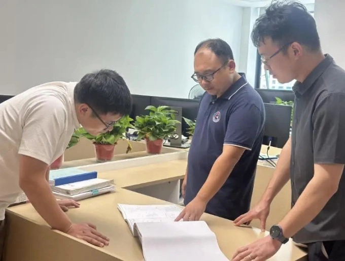 Bành Phái (giữa) thảo luận với đồng nghiệp tại công ty xây dựng ở tỉnh Hồ Nam, Trung Quốc, ngày 25/7. Ảnh: Sohu