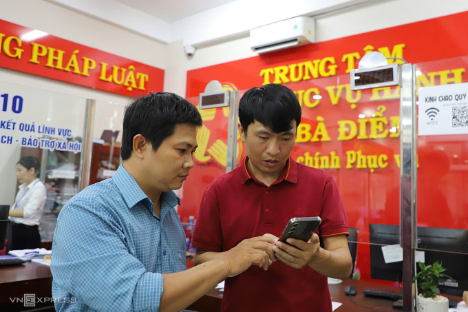 Anh Trịnh Hoàng Nam hướng dẫn cho người dân thao tác trên Cổng dịch vụ công quốc gia, ngày 31/7. Ảnh: Lê Tuyết