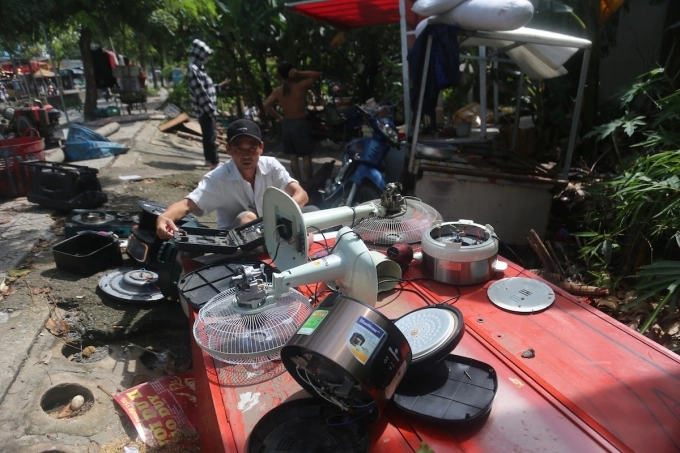 Ông Khải đem máy quạt, nồi cơm điện, bếp điện bị thấm nước sau mưa ngập ra ngoài đường để phơi. Ảnh: Đình Văn