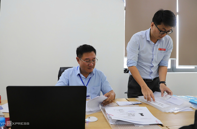 Ông Phan Ngọc Tân, Phó chủ tịch UBND phường Tăng Nhơn Phú kiêm Giám đốc Trung tâm phục vụ hành chính công phường, ký hồ sơ giữa giờ giải lao kỳ họp HĐND phường. Ảnh: Lê Tuyết