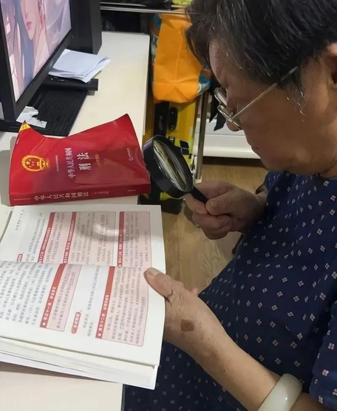 Bà Hà dùng kính lúp đọc bộ luật hình sự. Ảnh: Oriental Daily