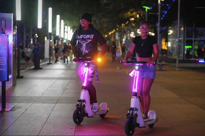 Người dân Houston lái scooter điện quanh công viên Discovery Green, ngày 26/7. Ảnh: HC