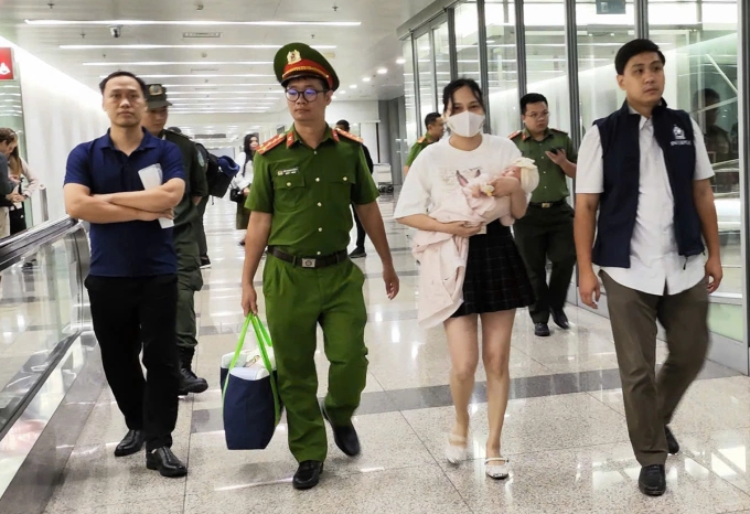 Ngô Thị Thêu đang bế con nhỏ bị dẫn giải về nước. Ảnh: Bộ Công an