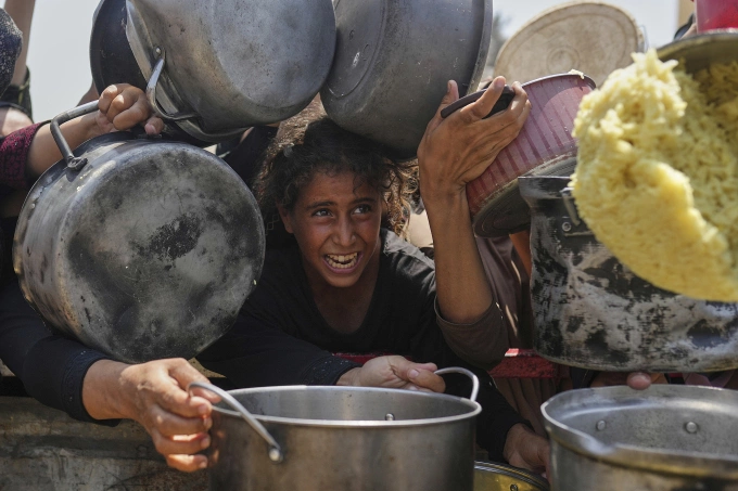 Một bé gái nhận thức ăn từ bếp cộng đồng ở Gaza City ngày 16/8. Ảnh: AP