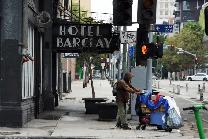 Người vô gia cư đẩy xe bên ngoài khách sạn Barclay ở khu trung tâm Los Angeles. Ảnh: NYP