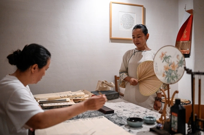 Yang Yun (phải), người sáng lập câu lạc bộ Không gian của cô ấy, ngắm khách hàng luyện thư pháp trong cơ sở tại Hàng Châu ngày 14/7. Ảnh: AFP