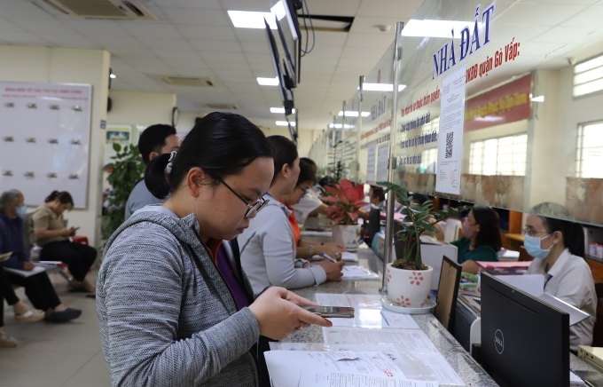 Người dân chụp lại hồ sơ từ điện thoại để gửi lên hệ thống trực tuyến khi làm thủ tục nhà đất tại Trung tâm phục vụ hành chính công phường Gò Vấp, ngày 6/8. Ảnh: Lê Tuyết