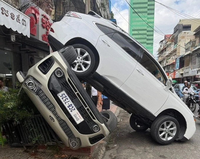 Chiếc Lexus ủn lật nghiêng xe Kia khi tài xế lùi xe từ hè xuống đường. Ảnh: Khmer Times