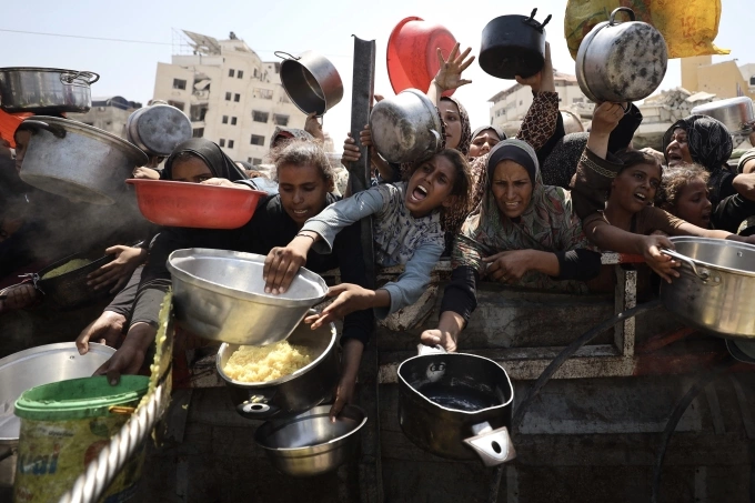 Phụ nữ, trẻ em Palestine xin cơm ở bếp từ thiện tại Gaza City ngày 23/8. Ảnh: AFP