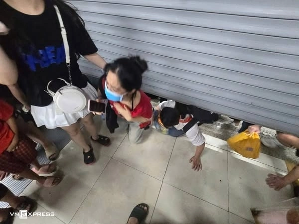 Nhiều người chui qua khe cửa cuốn để vào trong khi ga Cát Linh đóng cửa.