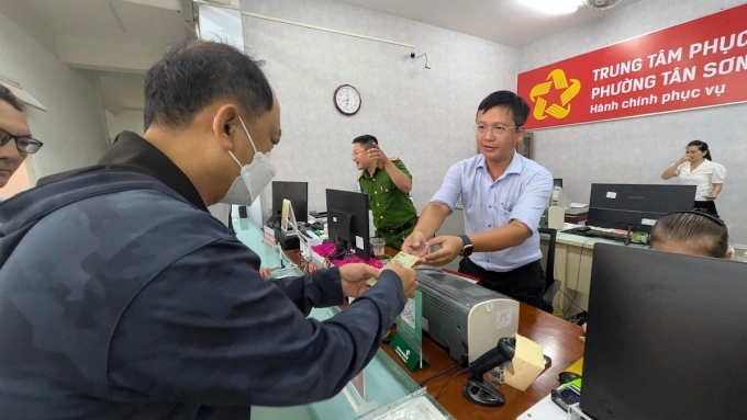 Cán bộ UBND phường Tân Sơn Nhất trao 100.000 đồng cho người dân. Ảnh: Đình Văn