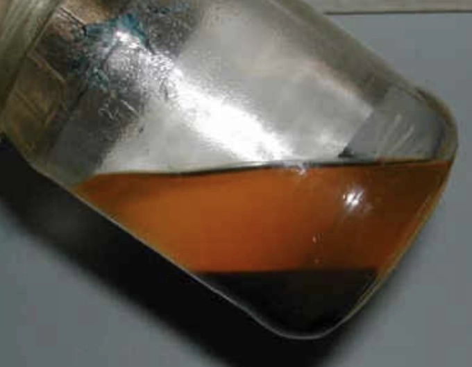 Hiện tượng tách lớp của xăng ethanol, lớp trên (màu cam) là xăng bị giảm nồng độ ethanol, lớp cặn đen ở dưới là hỗn hợp ethanol và nước. Ảnh: BP