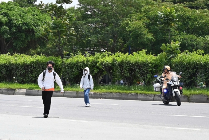 Hai sinh viên băng qua đường sau luật bị CSGT yêu cầu đi vào bên vỉa hè để xử lý. Ảnh: Hồ Đinh