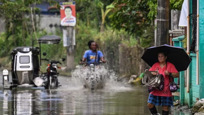 Người dân đi qua một khu vực ngập lụt ở Bulacan, miền trung đảo Luzon ngày 15/9. Ảnh: AFP