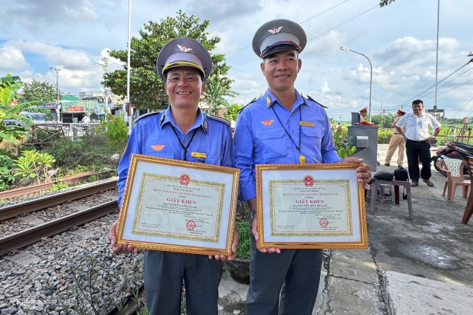 Anh Oánh (trái) và anh Hoàng - hai nhân viên trực trạm chắn vui mừng khi nhận được giấy khen. Ảnh: Phạm Linh