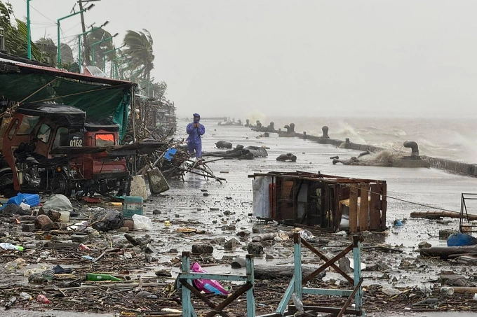 A man stands near debris on a waterfront road amid heavy rain due to weather patterns from Super Typhoon Ragasa in Aparri town, Cagayan province on September 22, 2025. Ảnh: AFP
