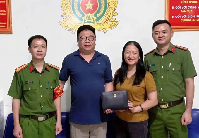 Chị Tú (thứ hai từ phải sang) trao trả lại chiếc túi đựng 400 triệu đồng cho anh Hiển (thứ hai từ trái sang). Ảnh: Công an cung cấp